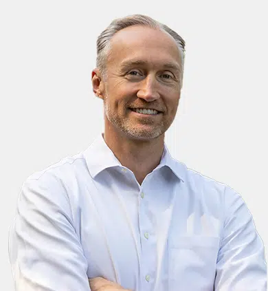 Professional headshot of smiling man in light blue shirt against white background.